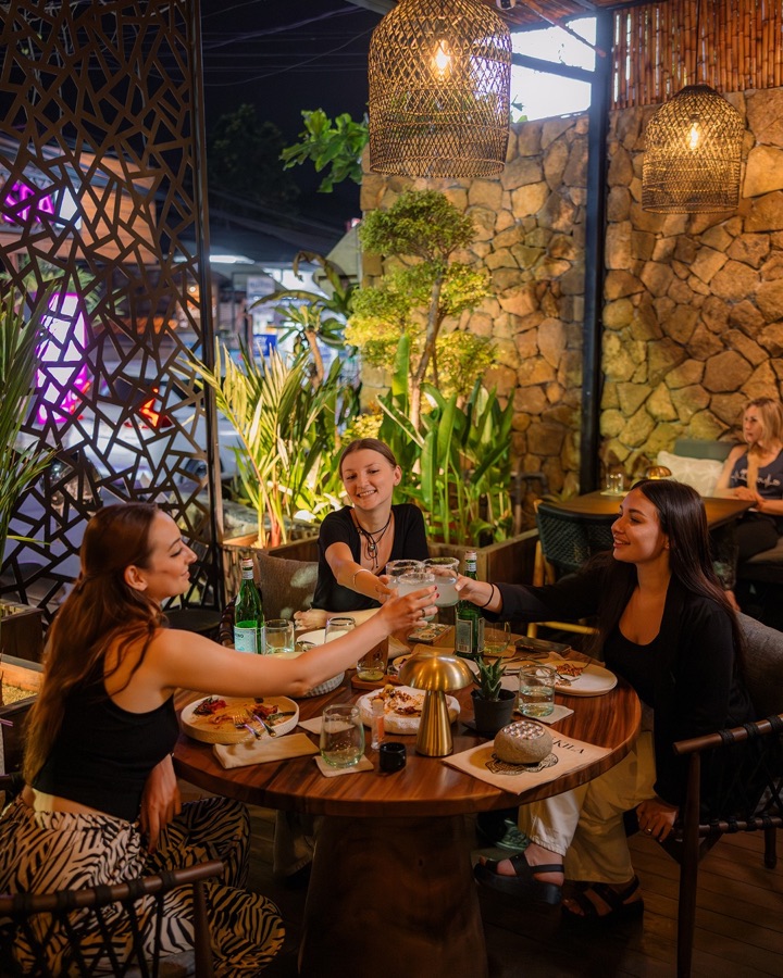 Friends toasting over dinner at Té Kila